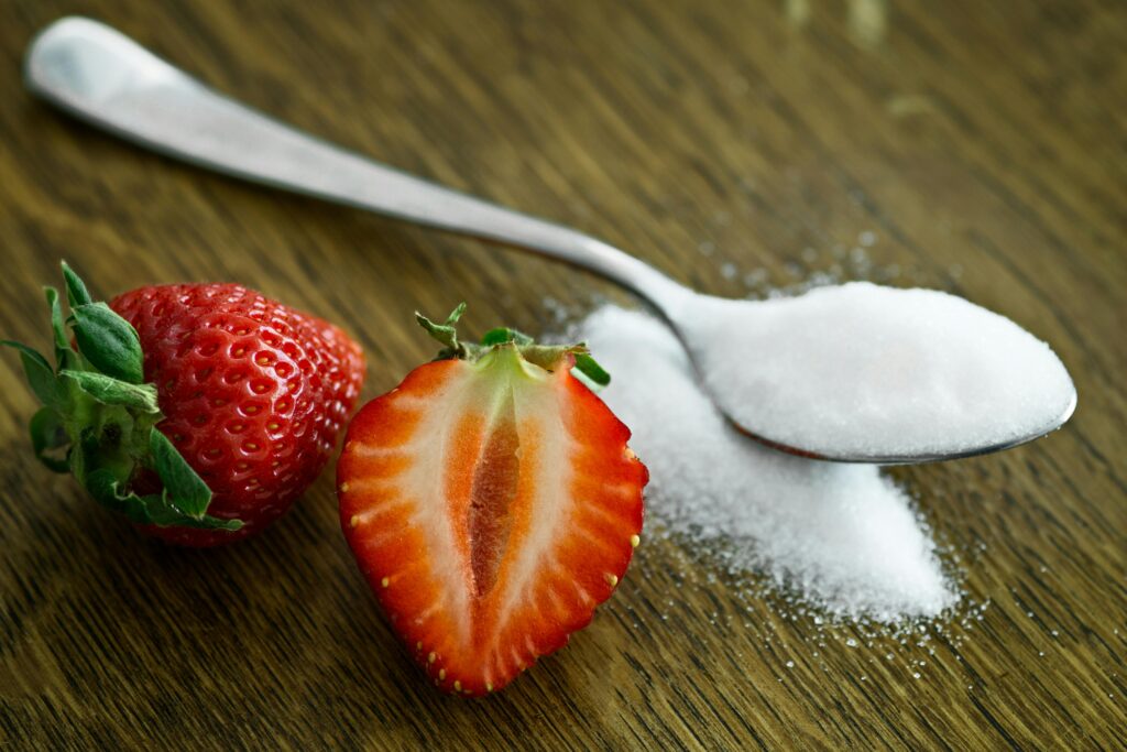 Close-up of fresh strawberries with sugar on a wooden table. Perfect for healthy dessert ideas.